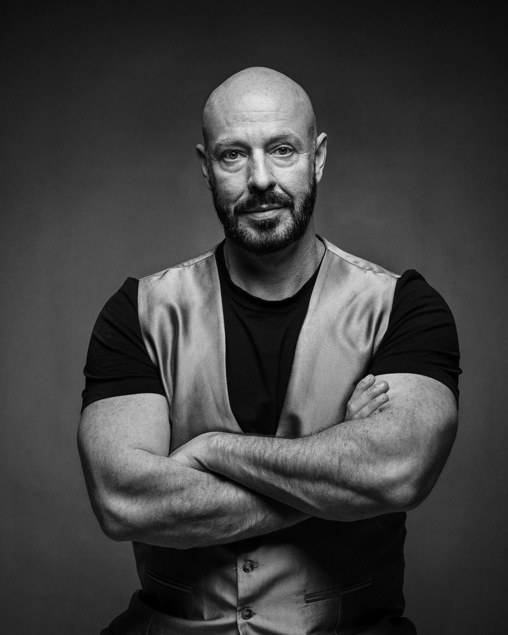 Schwarz-Weiß-Porträt eines muskulösen Mannes mit verschränkten Armen im Fotostudio