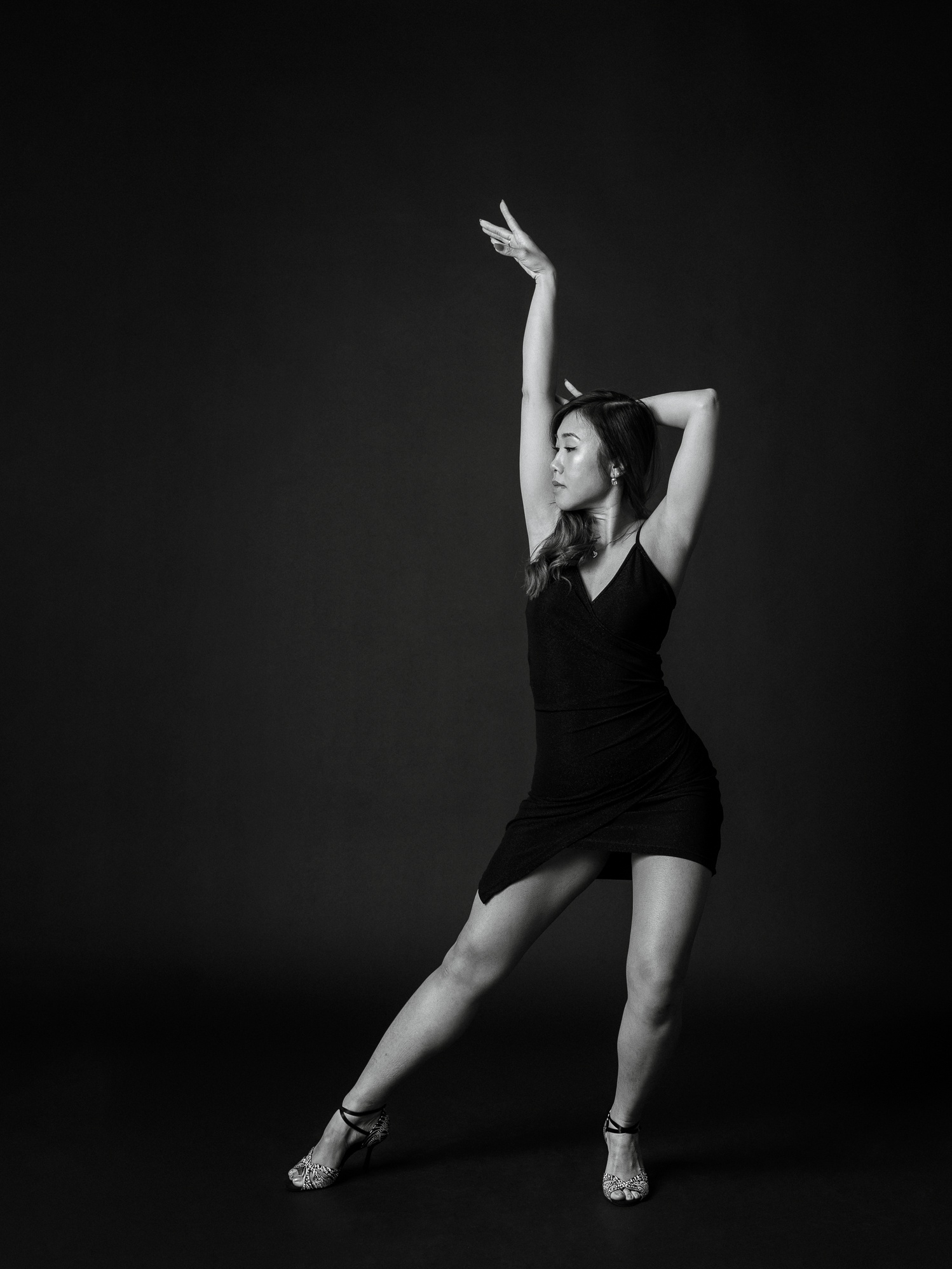 Schwarz-Weiß-Tanzporträt einer Frau in einer eleganten Pose vor dunklem Studiohintergrund