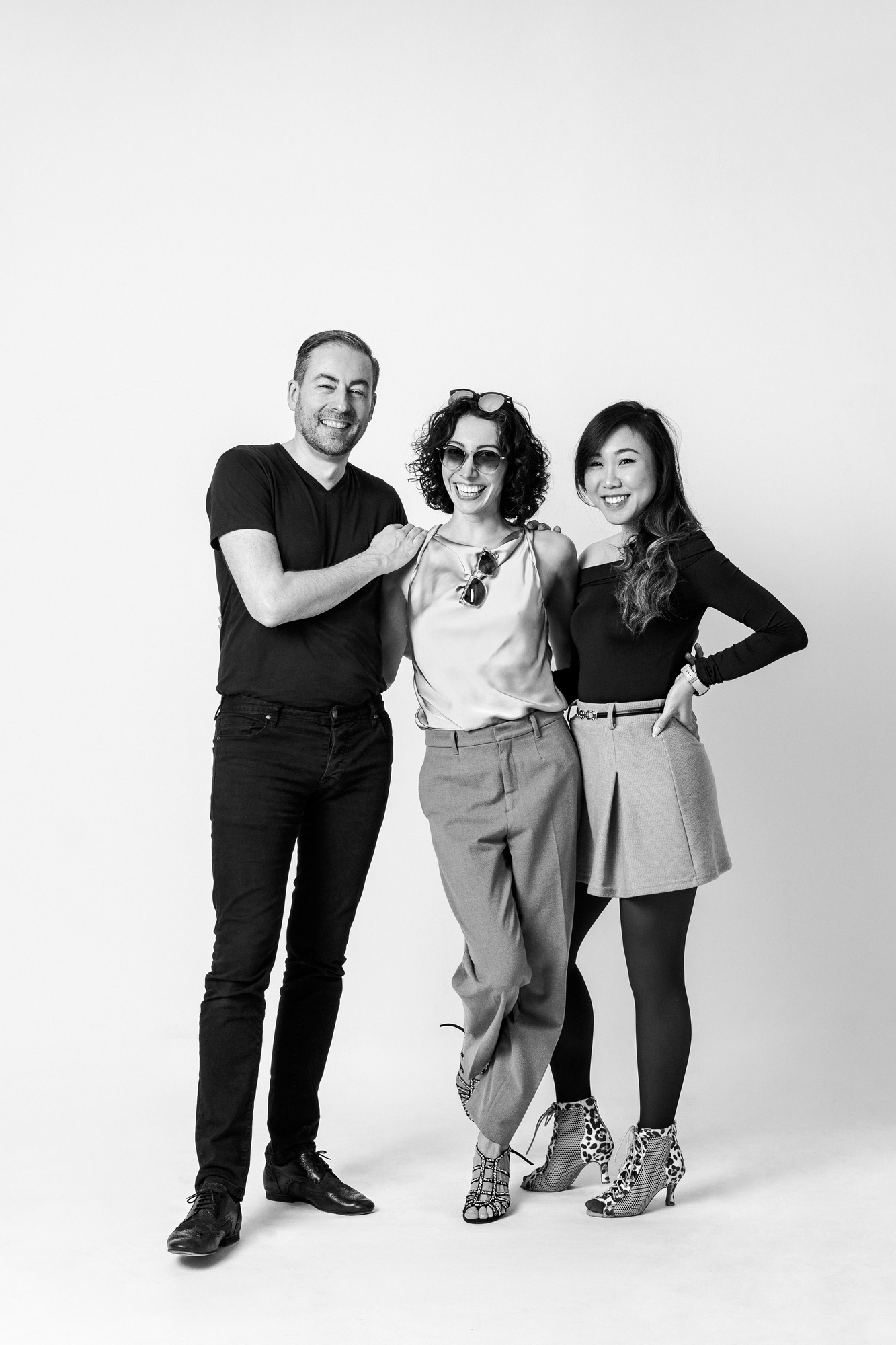Natural group portrait of three smiling people against a light studio background