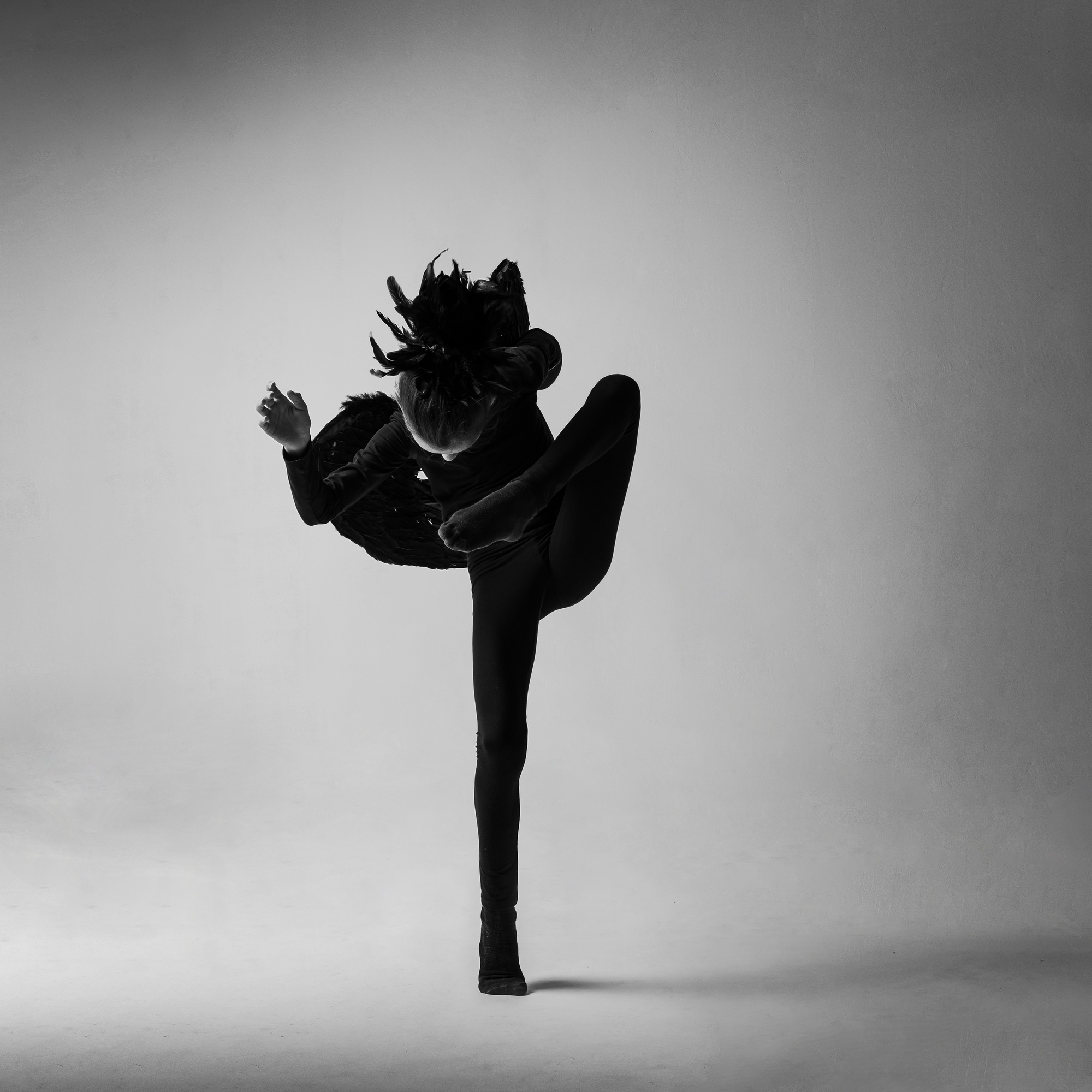 Schwarz-Weiß-Tanzporträt einer Frau in einer dynamischen Pose vor hellem Studiohintergrund