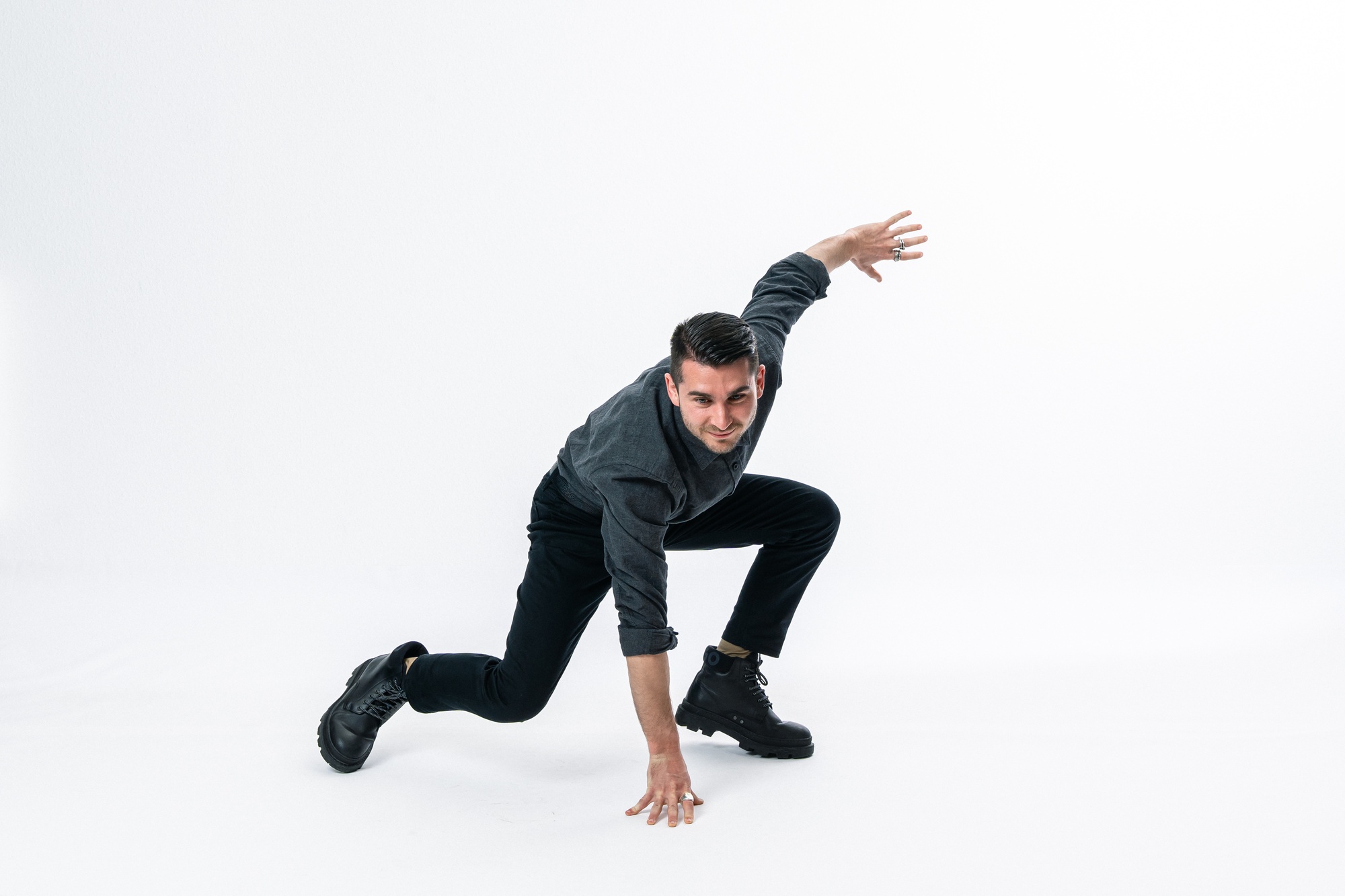Editorial portrait of a man in a dynamic pose against a light studio background